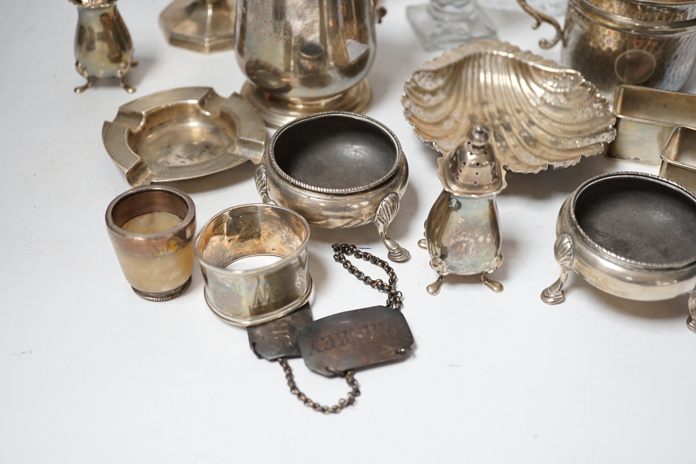 Assorted small silver including a christening mug, a planished porringer, pair of George V sugar casters, butter shell, ashtray, two mounted glass posy vases, four condiments, four napkin rings, a mounted glass cruet bot